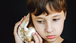 Foto di un bambino che ascolta il suono di una conchiglia, per l'articolo Ting Jin l'ascolto nelle Arti Marziali tradizionali cinesi